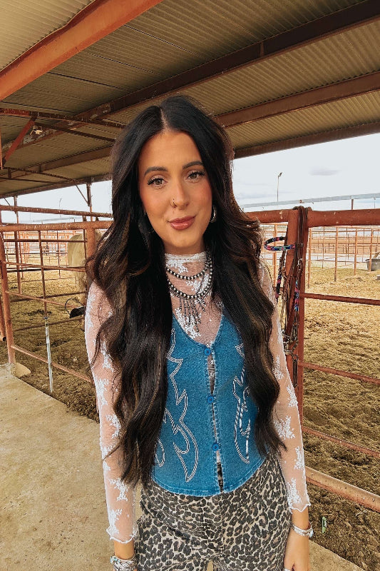 Woman in a blue top with white patterns and leopard print pants standing in a barn.