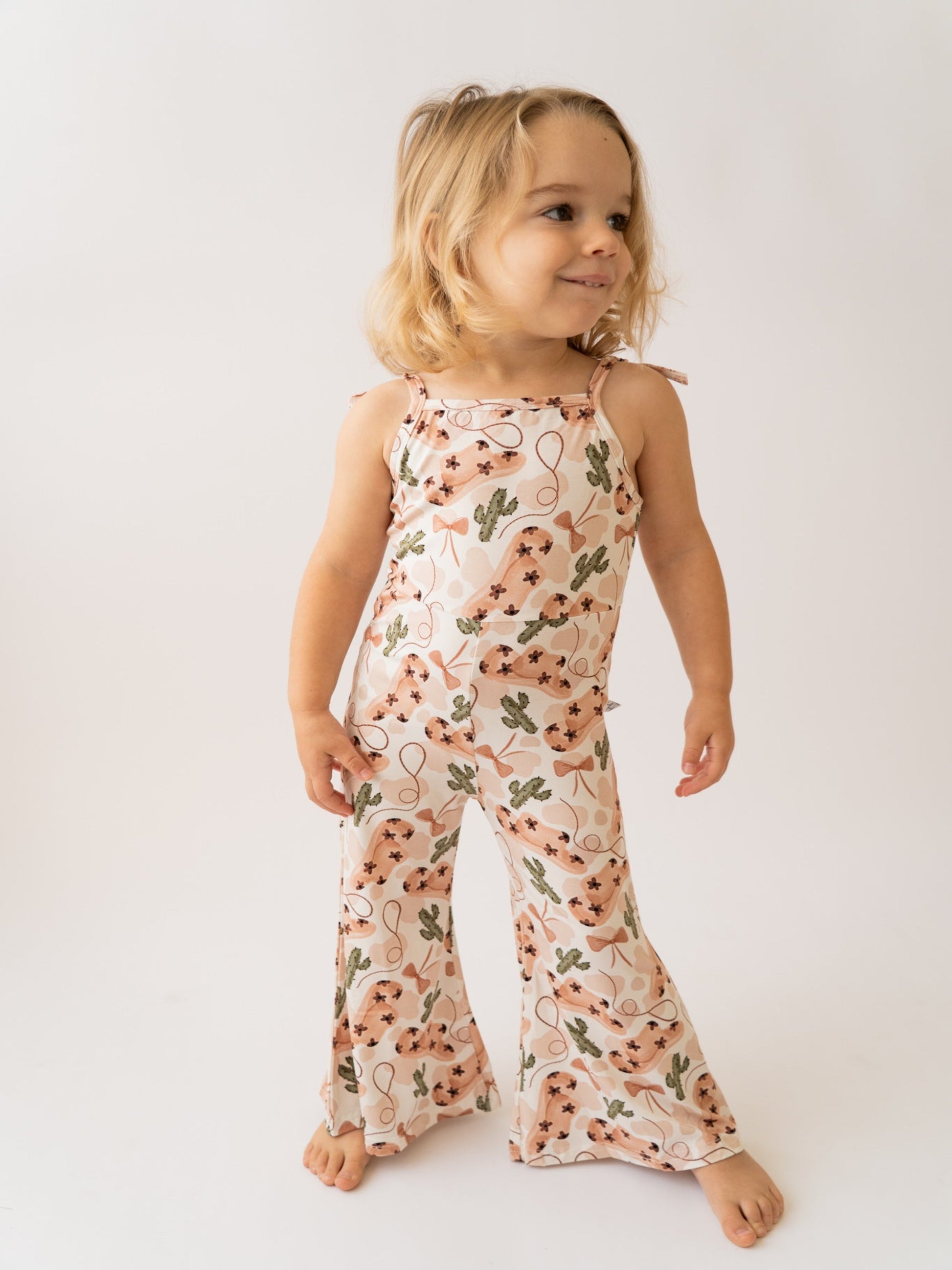 Child wearing a floral jumpsuit on a plain background