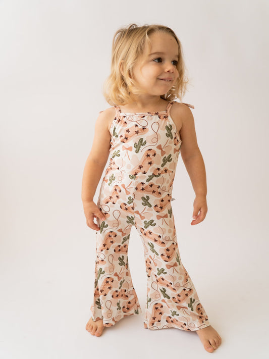 Child wearing a floral jumpsuit on a plain background