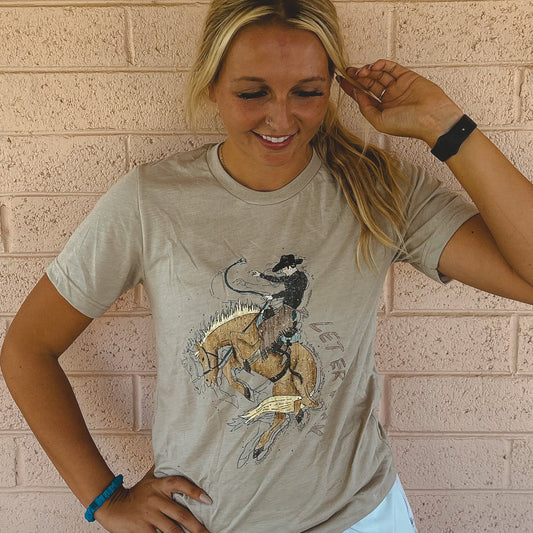 Woman wearing a t-shirt with a graphic design of a person riding a horse against a brick wall.