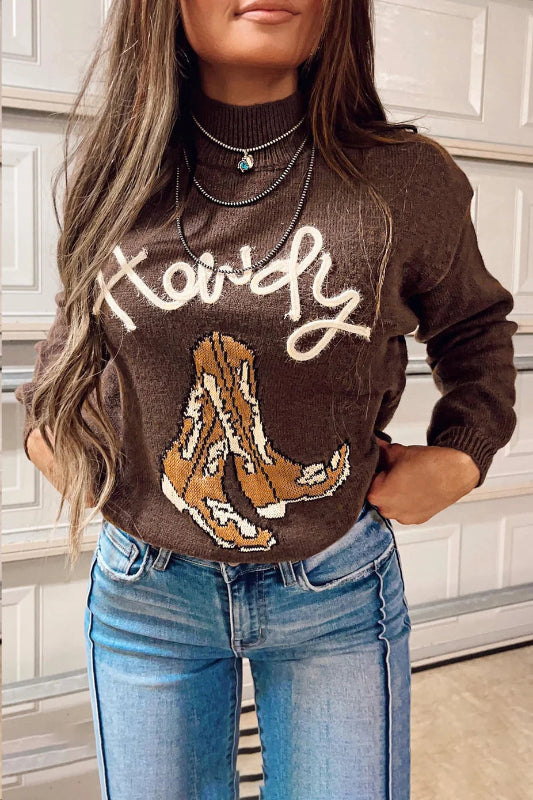 Person wearing a brown sweater with a graphic design and text, standing in a kitchen.