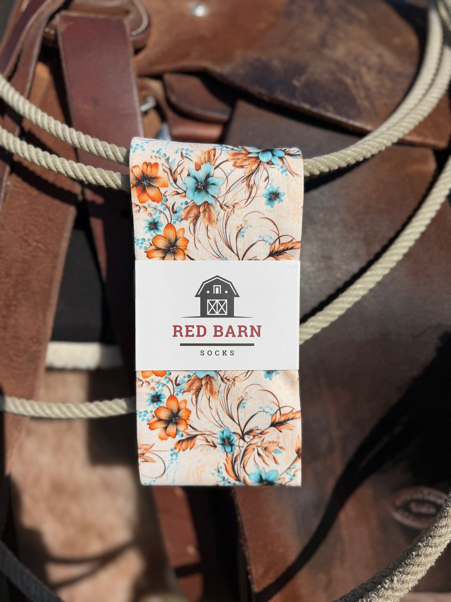 Floral packaging with 'Red Barn' branding on a background of a brown leather saddle.
